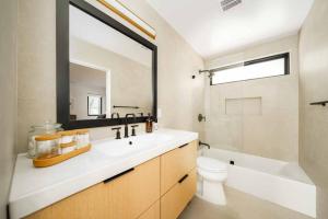 a bathroom with a sink and a toilet and a mirror at Skyline Serenity Lux Hilltop Retreat Spa and Sauna in Los Angeles