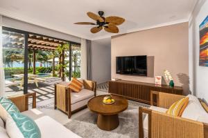 un soggiorno con un divano e una TV di Andochine Villas Resort & Spa Phu Quoc - All Villas with Private Pool a Phu Quoc