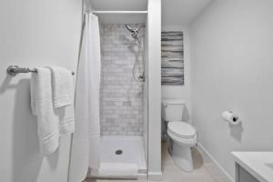 La salle de bains blanche est pourvue d'une douche et de toilettes. dans l'établissement Charming Mt. Adams 1BR - Near Downtown & Stadiums, à Cincinnati