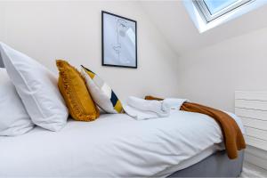 a white bed with yellow pillows on top of it at Creative stylings 2 Bedroom in Wembley Park in London