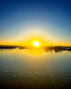 einen Sonnenuntergang über einem Wasserkörper mit Sonnenuntergang in der Unterkunft Uros Habitación Suite in Puno