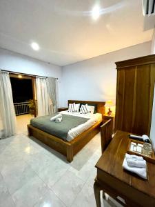 a bedroom with a bed and a table and a desk at Chua Guest house Canggu in Canggu