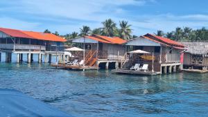 a group of houses on the water with chairs at Cabañas Narasgandup (Naranjo Chico) in Mamartupo