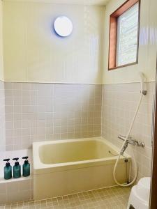 ein Bad mit einer grünen Badewanne und einem Fenster in der Unterkunft Pyrenees Cottage - Vacation STAY 24861v in Hakuba