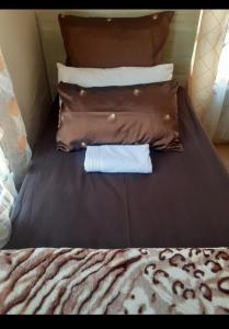 a bed with three pillows and a shirt on it at Rona Thina House in Pimville