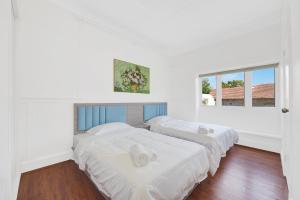 two beds in a room with white walls and wood floors at Dream Vintage Place in Chatswood in Sydney