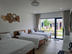 um quarto de hotel com três camas e uma varanda em Myhoa Lagoon - Kiting Town em Phan Rang-Tháp Chàm