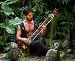 a man playing a guitar in a forest at Unicorn Reborn - Peaceful Rentals in San Marcos La Laguna