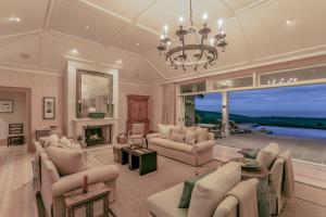 a large living room with a chandelier and a fireplace at Rosewood Kauri Cliffs in Matauri Bay