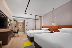 Home2 Suites by Hilton Guangzhou Baiyun Airport West في هوادو: غرفة فندقية بسريرين ومكتب