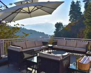 eine Terrasse mit Sofas, Sonnenschirm und Tisch in der Unterkunft Mahantam Luxury Stays in Nagar