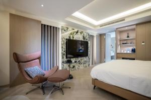 1 dormitorio con 1 cama, 1 silla y TV en Voyager Hotel, en Tainan