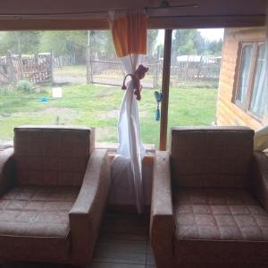 um vestido de noiva pendurado numa janela com dois sofás em Casa estilo cabaña em El Bolsón