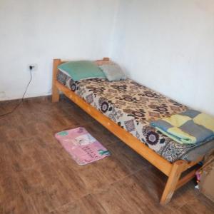 a small bed in a room with a wooden floor at Casa estilo cabaña in El Bolsón