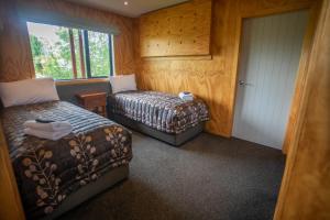 a bedroom with two beds and a door with a window at Musterers Accommodation Fairlie in Fairlie