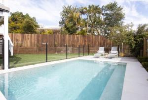 una piscina con dos sillas y una valla en Matilda - Noosa Heads, en Noosa Heads