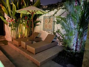 a patio with benches and an umbrella and plants at Pennylane Villa in Seminyak