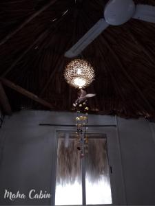 a ceiling fan and a chandelier in a room at Maha cabin beach access in Mahahual