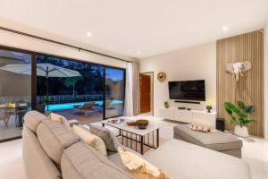 a living room with a couch and a large window at Jungle Retreat: Sereniwoods Villa Private Pool 3br in Koh Samui 