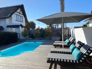 two lounge chairs and an umbrella next to a pool at CANAL GUEST HOUSE - Waterfront Accommodation in St Francis Bay