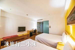 a hotel room with two beds and a television at Hotel Leisure Tamsui in Tamsui