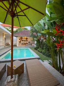 a swimming pool with a green umbrella and some plants at Pennylane Villa in Seminyak