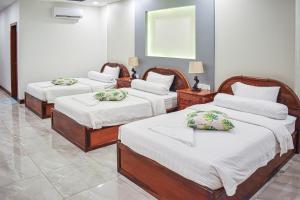 1 dormitorio con 3 camas con sábanas blancas en Dara Express Inn by Angkor Green Gardens, en Phumĭ Thnál