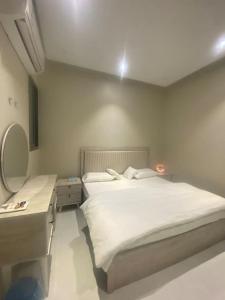 Schlafzimmer mit einem weißen Bett und einem Spiegel in der Unterkunft غرفتين بدخول ذاتي in Al Kharj