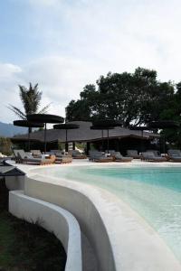 a swimming pool with chairs and umbrellas next to a resort at Toteme Glamping and Hot Spring Kintamani in Kubupenlokan