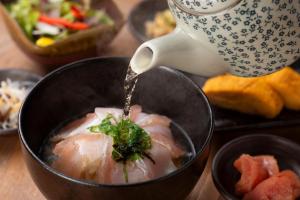 a person is stirring a bowl of food at HOTEL MYSTAYS Fukuoka Tenjin in Fukuoka