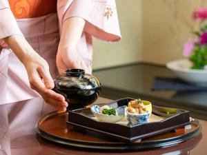 a woman holding a tray of food on a table at Rihga Royal Hotel Kokura Fukuoka in Kitakyushu