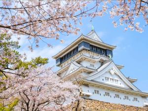 a japanese castle withakura trees in front of it at Rihga Royal Hotel Kokura Fukuoka in Kitakyushu