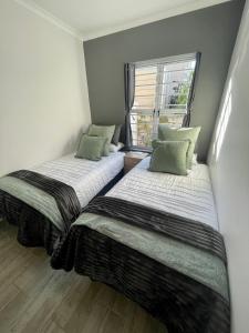 two beds in a room with a window at Claptons Cottage 12 in Jeffreys Bay