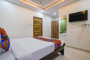 1 dormitorio con 1 cama y TV en la pared en FabHotel Cozy, en Hyderabad