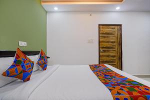 Un dormitorio con una cama con almohadas de colores. en FabHotel Cozy, en Hyderabad