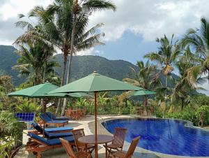 een resort met een zwembad en stoelen en een tafel met parasols bij Sekumpul Bali Hidden Space in Singaraja