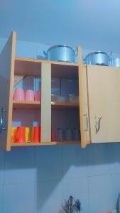 a kitchen cabinet with dishes and pots and pans at Nabbynates bnbs in Eldoret