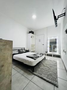 a white bedroom with a large bed and a rug at CASA AMBAR in Tijuana