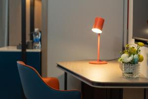 a desk with a lamp and a table with chairs at Holiday Inn Express Changsha Development Zone, an IHG Hotel in Xingsha
