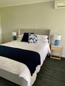 Un dormitorio con una cama grande con almohadas azules y blancas. en Springwood Cottage, en Denmark