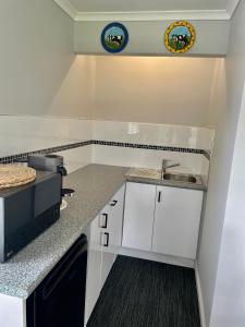 Una cocina con gabinetes blancos y un fregadero. en Springwood Cottage, en Denmark
