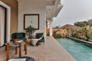 uma sala de estar com uma piscina e um sofá e cadeiras em Eclectic Luxury 3bhk Villa with Private Pool em Mapuçá