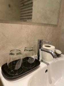 a tray with two glasses sitting on top of a sink at CK2 Hotel SHA EXTRA PLUS in Bangkok