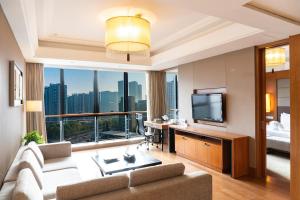 Holiday Inn Hangzhou CBD, an IHG Hotel في هانغتشو: غرفة معيشة بها أريكة وتلفزيون