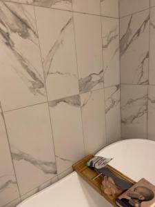 a bathroom with a tub and a marble tile wall at CHATHAM TERRACE LAKE HOUSE in Bridgeport