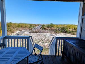 a porch with a table and chairs on a beach at Harbor Island D112 in Oceanmarsh Subdivision