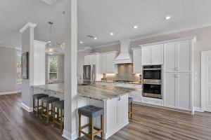 a kitchen with white cabinets and a island with bar stools at Chateau Coquina in Jacksonville