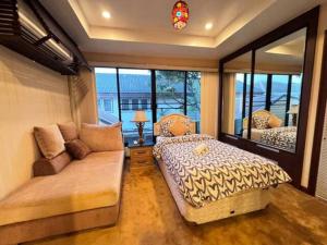 een slaapkamer met 2 bedden, een bank en een raam bij 曼谷独栋Lat Phrao精品别墅 in Ban O Pao