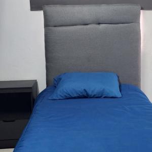 Bett mit blauem Kissen darüber in der Unterkunft El Hostalito Metepec in Toluca de Lerdo