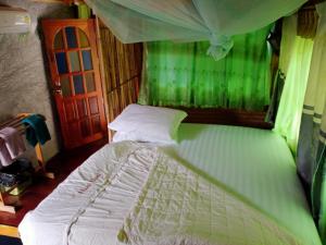 - un lit dans une chambre à baldaquin vert dans l'établissement Comon Bungalow HaadChaoPhao, à Haad Chao Phao